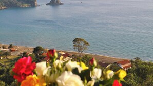A coastal landscape with a rocky outcrop, beach, and residential buildings. - Beachfront Holiday House Eftichia (Corfu)