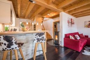 Une cuisine moderne avec un plafond en bois, un canapé rouge et un coin bar avec des tabourets.