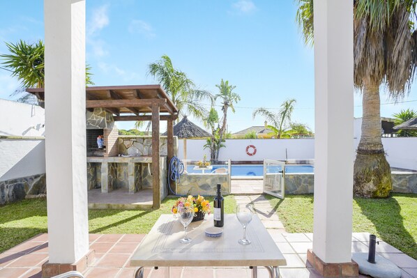 A patio with a table set for two, a bottle of wine, and a glass of water.