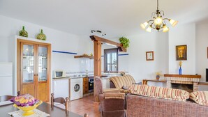 A kitchen with a microwave, washing machine, and a dining area with a table and chairs.