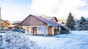 A wooden building with a sloped roof, a wooden door, and a small porch area.