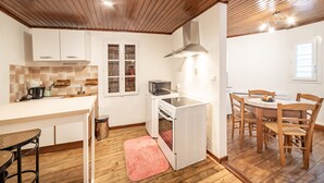 A compact kitchen with white cabinets, a built-in oven, and a dining area with wooden chairs and a table.