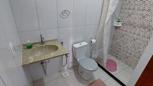 A bathroom with a sink, toilet, and shower area. - Guest House Palmeiras (Cabo Frio)