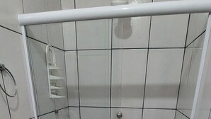 A small, tiled bathroom with a shower, toilet, and sink. - Guest House Palmeiras (Cabo Frio)