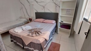 A bedroom with two beds, a marble-patterned wall, a mirror, and a shelf with items. - Guest House Palmeiras (Cabo Frio)