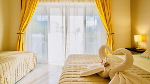 A hotel room with two beds, a large window with curtains, a nightstand with a lamp, and a decorative swan towel arrangement. - Room-playacar - Deluxe Family Comfort Ba (Playa del Carmen)