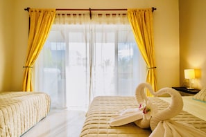 Une chambre d’hôtel avec deux lits, une fenêtre avec des rideaux et une décoration en forme de cygne faite avec des serviettes.