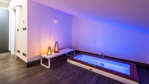 Un baño moderno con una bañera grande, un banco y una lámpara de pared.