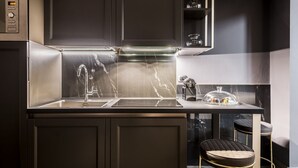 Una cocina moderna con gabinetes oscuros, una campana extractora de acero inoxidable y un salpicadero de mármol.