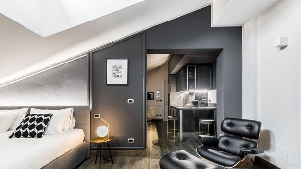 Una habitación de hotel moderna con una cama, un escritorio, una silla y un kitchenette.