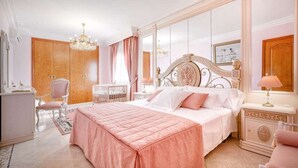 Un dormitorio con una cama grande, tocador, sillón, cuna y araña.