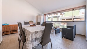 Un comedor con una mesa dispuesta para cuatro personas, un banco de madera y una silla de mimbre.
