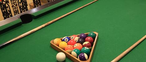 A pool table with a triangular rack of billiard balls and a cue stick.