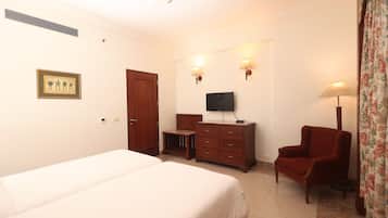 Una habitación de hotel con cama, televisor, cómoda, silla y lámpara.