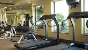 A gym with treadmills, weight machines, and a TV screen. - Savoy Suites Noida (Noida)