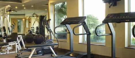 A gym with treadmills, weight machines, and a TV screen.