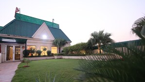 A building with a green roof, a well-maintained lawn, and a small palm tree.