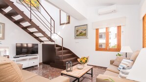 A living room with a staircase, a flat-screen TV, a wooden coffee table, and a sofa.