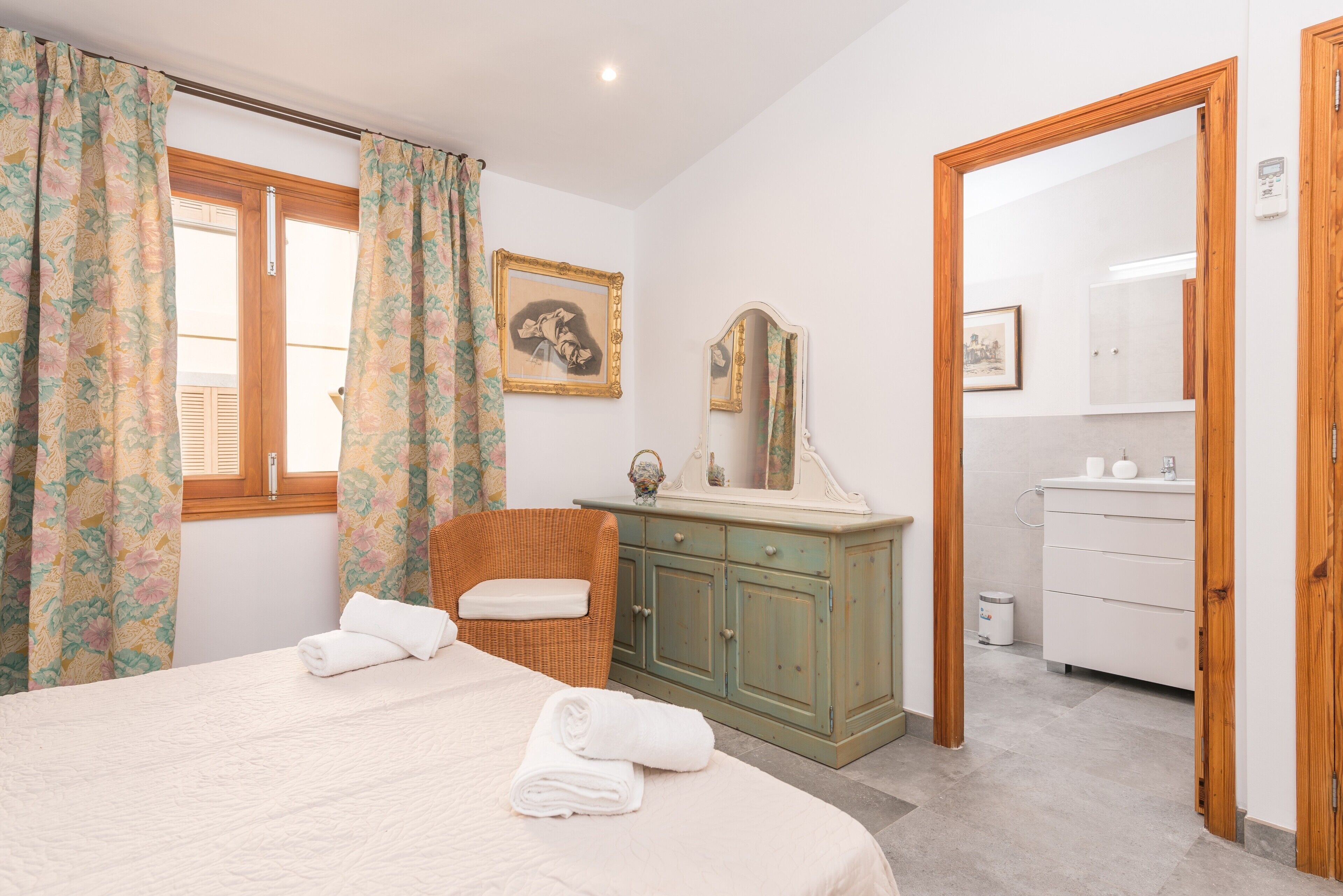 A bedroom with a bed, a dresser, a mirror, and a window with curtains.