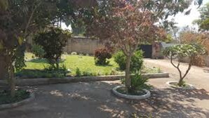 A garden with a paved path, various shrubs, and a lawn. - Dream Heart Lodge (Ndola)
