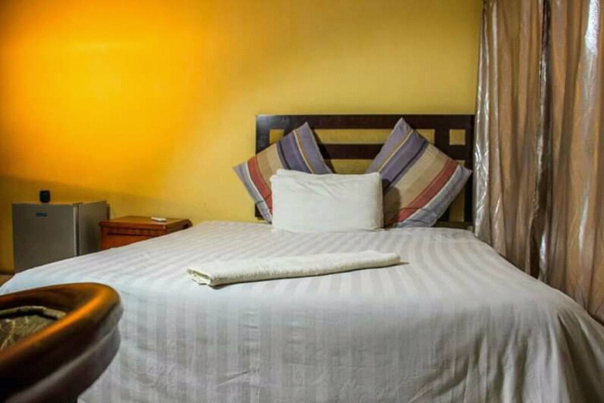 A hotel room with a bed, a nightstand, and a suitcase.