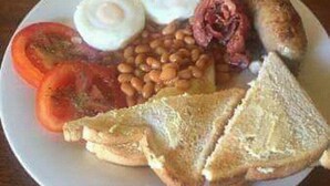 A plate with eggs, sausages, beans, tomatoes, and toast. - Dream Heart Lodge (Ndola)