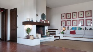A living room with a fireplace, a sofa, a coffee table, and framed pictures on the wall.