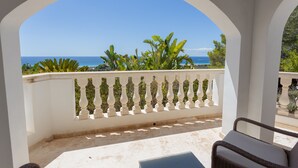 A balcony with a view of the sea, white balustrades, and outdoor furniture. - Stunning villa with pool & sea view – Villa Maitreya (san jaime, son bou, Alaior)