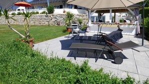 A patio with outdoor furniture, a large umbrella, and a stone wall. - Wonderful Apartment in the house Seeblick (Salem)