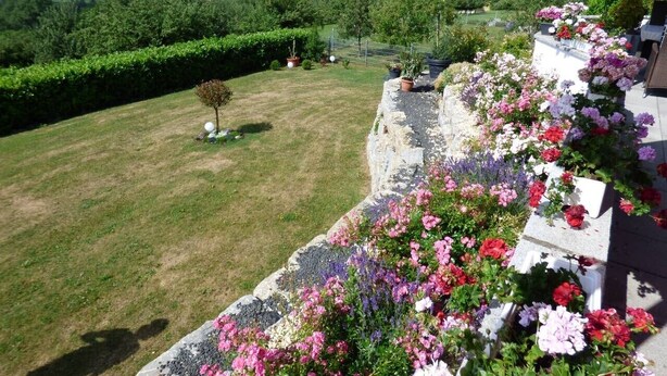 A garden with a stone wall, flowers, and a view of the countryside. - Wonderful Apartment in the house Seeblick (Salem)