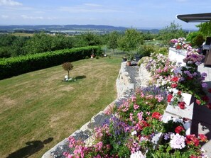 A garden with a stone wall, flowers, and a view of the countryside. - Wonderful Apartment in the house Seeblick (Salem)
