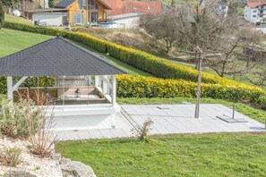 A gazebo with a tiled roof, a small seating area, and a paved patio. - Wonderful Apartment in the house Seeblick (Salem)