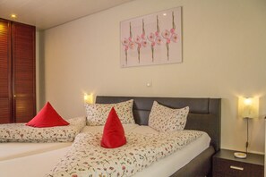 A double bed with floral bedding, two red pillows, a headboard, bedside lamps, and a wall-mounted picture. - Wonderful Apartment in the house Seeblick (Salem)