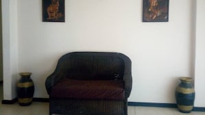 Una habitación con un sofá de mimbre, dos jarrones y dos cuadros en la pared.