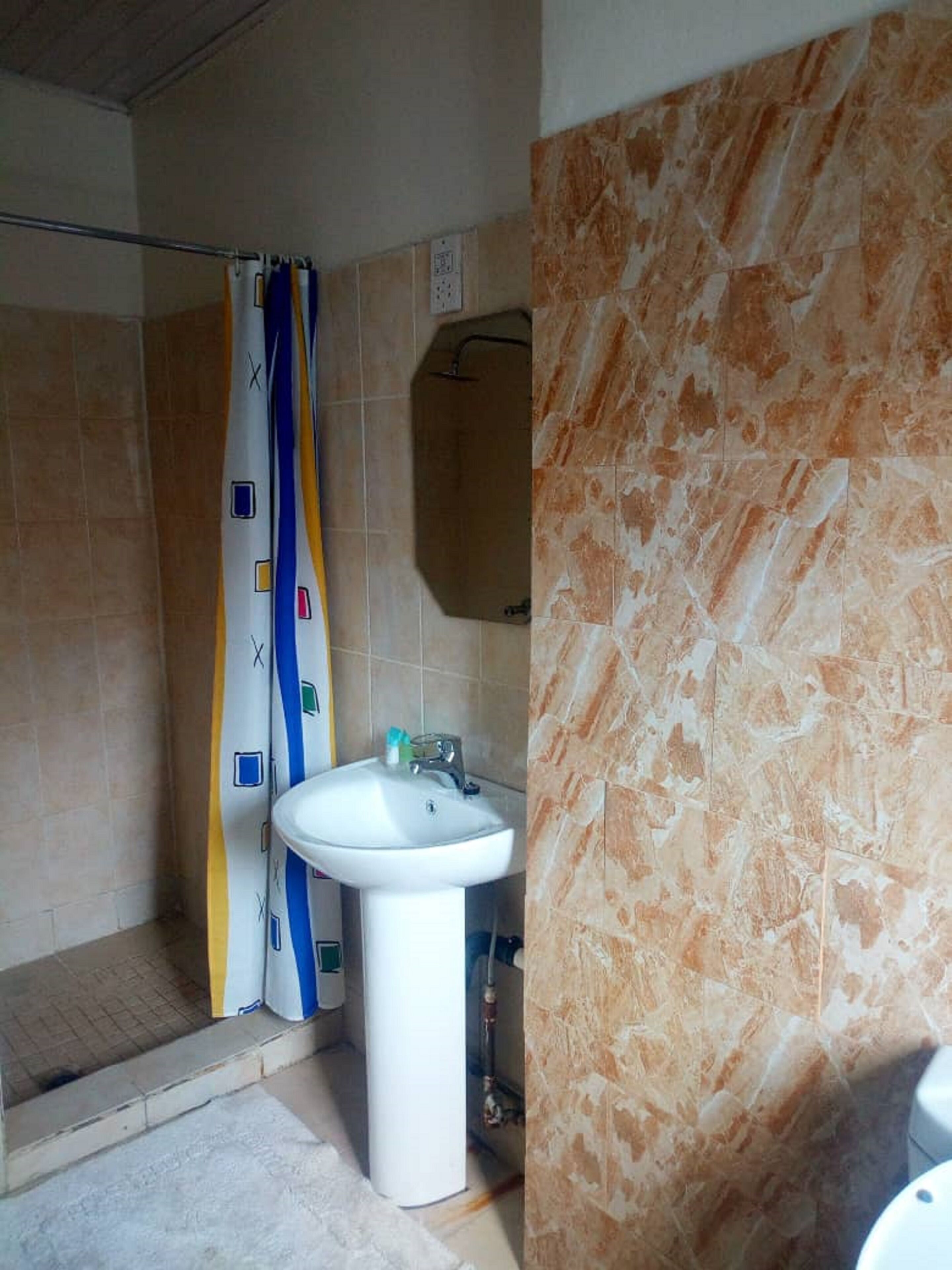 Ein Badezimmer mit Dusche, Waschbecken und Spiegel.