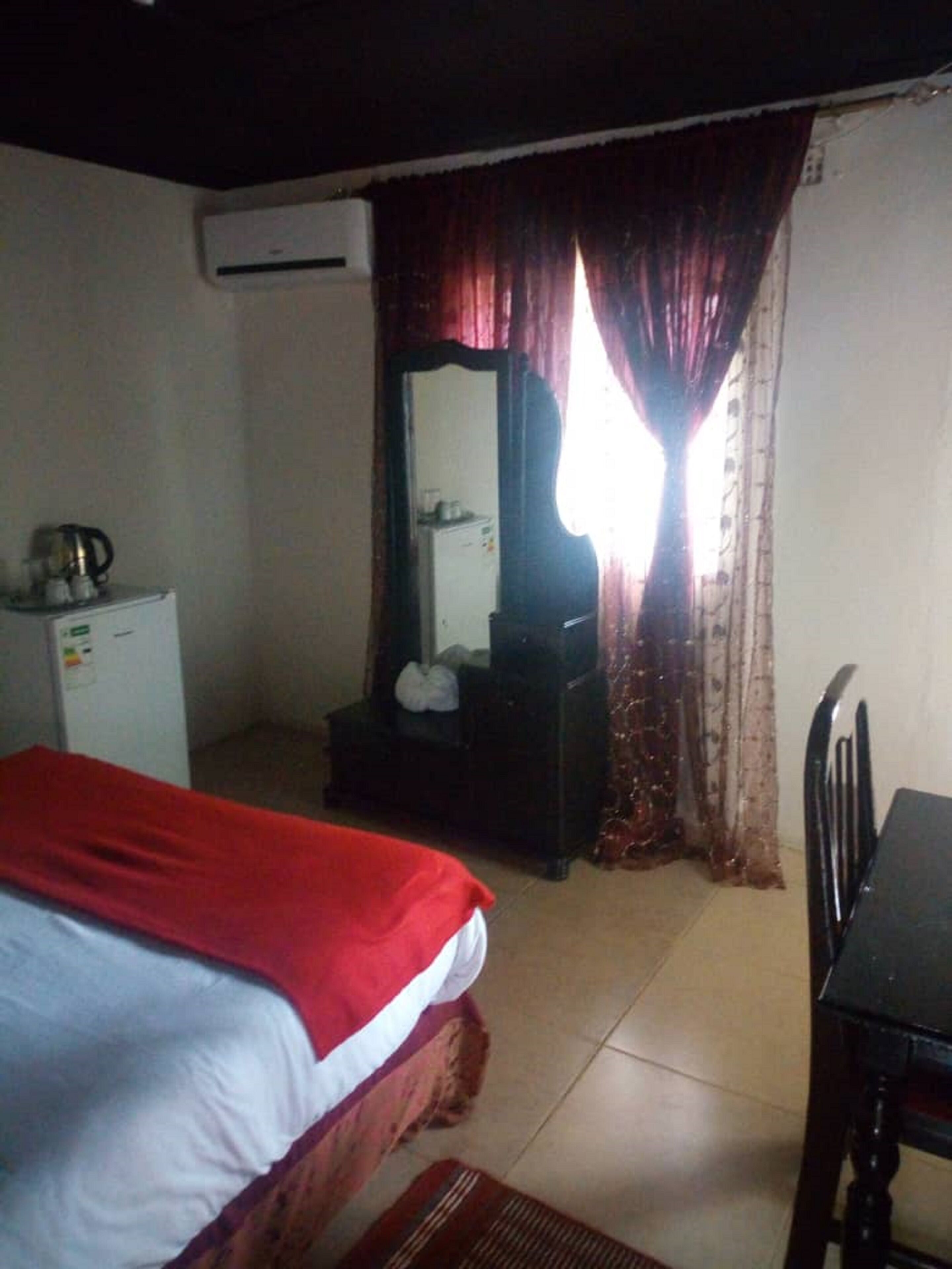 A room with a bed, a desk, a mirror, and an air conditioning unit.