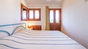 Quarto com cama, porta de madeira, janela e espelho na parede.