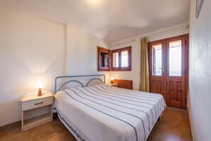 A bedroom with a bed, bedside tables, a wooden wardrobe, and a window with curtains.