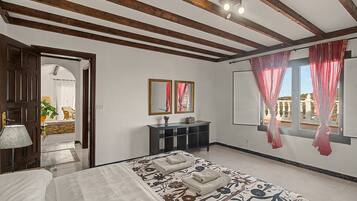 A hotel room with a bed, a console table, a mirror, and a window with curtains.