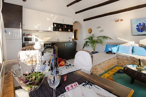 A compact living space with a kitchenette, dining area, and a sofa with patterned cushions. - Clara Suite 3 with Large Pool, Stunning Views, Terrace and Garden (Lanzarote)
