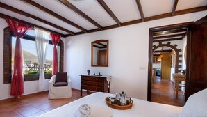 Ein Schlafzimmer mit Bett, Stuhl, Schminktisch und Frühstückswagen.