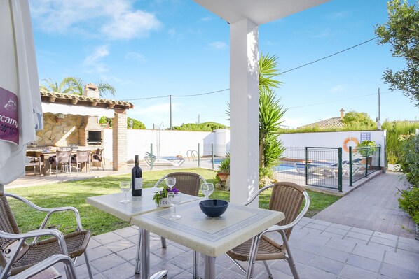 Un patio con una mesa, sillas, una botella de vino y un bol.