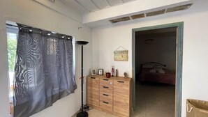 A room with a wooden dresser, a floor lamp, and a bed in the background. - The Dockside Dwelling Corfu Island (Corfu)