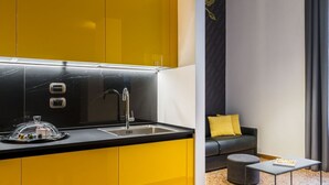 A modern kitchen with yellow cabinets and a black countertop, a sink, and a glass food cover. - 18 · Extreme design style - Bologna Downtown Apartment (Bologna)