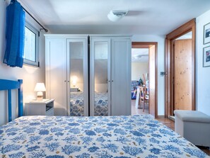 Una camera da letto con un letto, un comodino, una lampada, un armadio e una porta che dà su un'altra stanza.