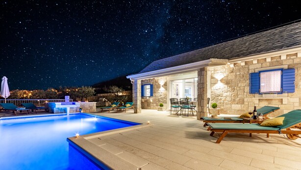 A swimming pool with lounge chairs and a stone building with a glass door. - Villa Blue Sky (Bol)