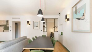 A conference room with a long table, green chairs, a grey sofa, and a framed abstract painting.