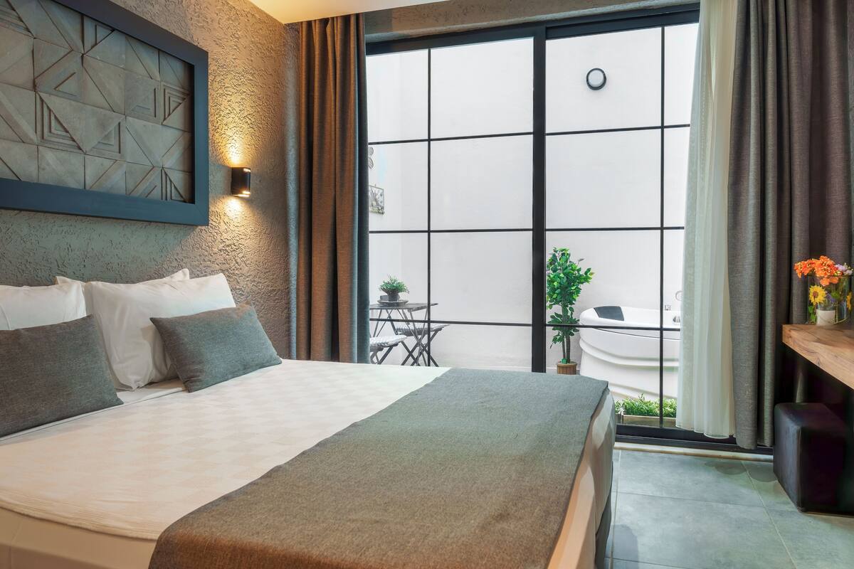 Moderni hotellihuone, jossa on suuri sänky, näköala ulos ja pieni parvekealue.