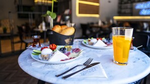 Una mesa de comedor con platos de comida, un vaso de jugo de naranja y cubiertos.