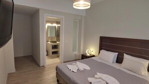 A hotel room with a bed, a bedside table with a lamp, a mirror, and a bathroom visible through an open door. - Villa Leo 1 , Dassia , Corfu (Corfu)